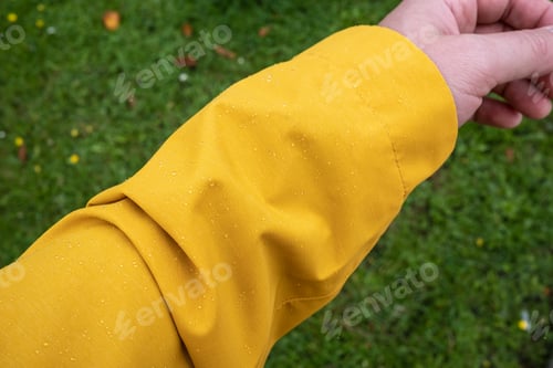 Preview: Yellow Raincoat Sleeve with Raindrops on Grass
