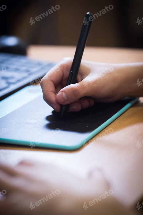 Preview: Vertical shot of a hand drawing on a graphic design tablet with a black pen
