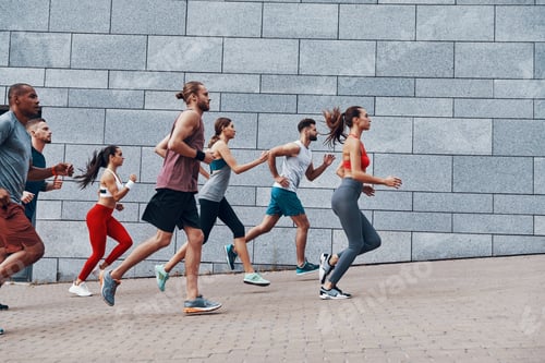 Preview: Group Of Young People In Sports Clothing Jogging While Exercising On The Sidewalk Outdoors
