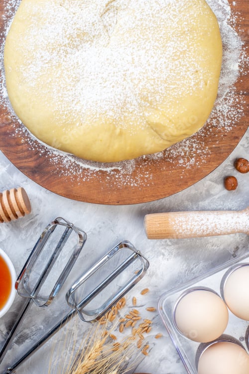 Preview: Top view of raw pastry on round wooden board grater and eggs spikes on ice background