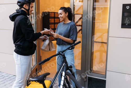 Preview: Young woman receiving a package from a delivery man at the apartment building