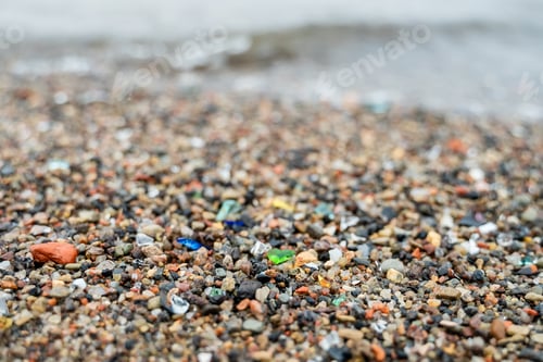 Preview: Close-up of glass pieces on beach mixed with sand, small stones, sea waves in background