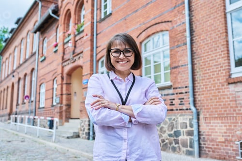 Preview: Portrait of female teacher, facade of educational building background