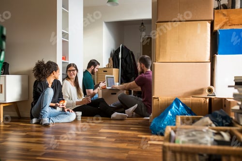 Preview: Group of friends resting on floor surrounded by moving boxes