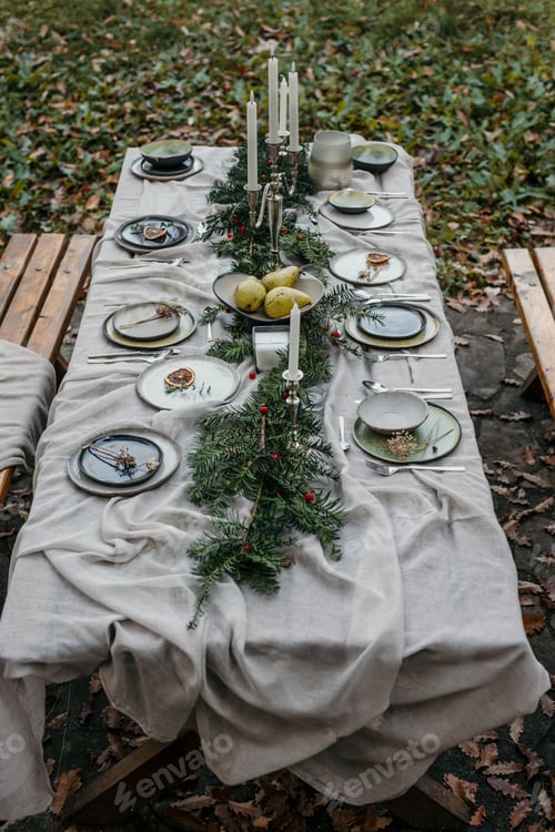 Preview: Christmas table setting decorated with greenery, candles and pears in the garden