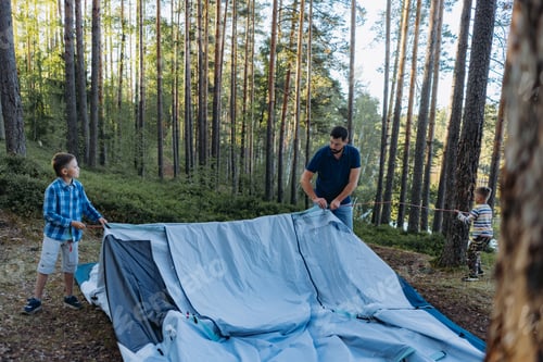 Preview: children helping father to put up a tent. Family camping concept