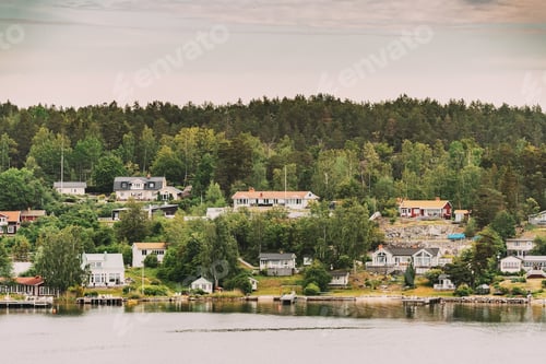 Preview: Sweden. Beautiful Swedish Wooden Log Cabins Houses On Rocky Island Coast In Summer Day. Lake Or