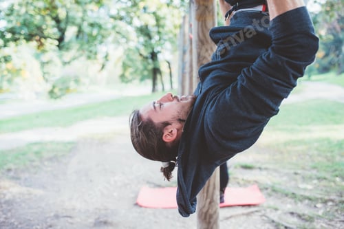 Preview: Man training outdoor in a park using rings