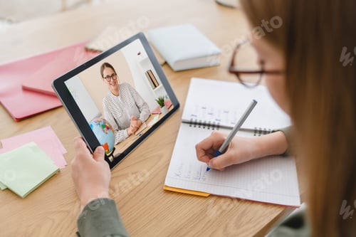 Preview: Schoolgirl preteen pupil student e-learning, doing homework writing in copybook on distance online