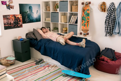 Preview: Young man lying on bed while having rest and thinking