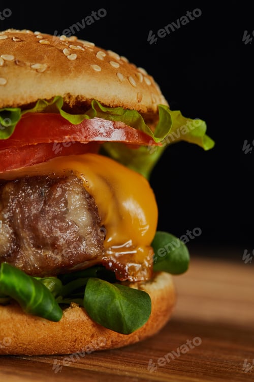 Preview: close up of delicious meat burger with cheese, greenery, tomatoes and sesame