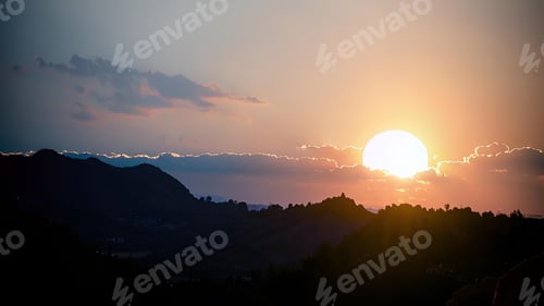 Preview: Scenic sunset over mountains with a glowing sun.