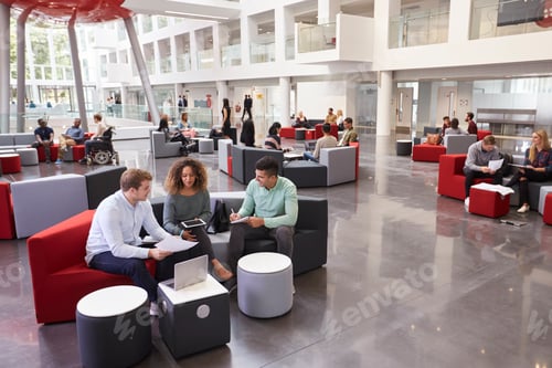 Preview: Students sitting in university atrium, three in foreground