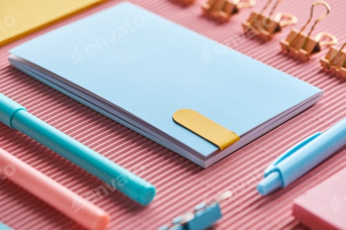 Preview: selective focus of notebook and colorful stationery supplies on pink