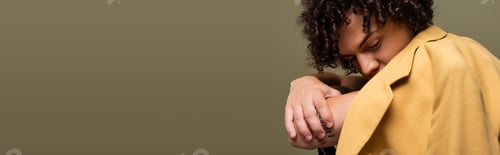 Preview: african american guy with curly hair obscuring face with yellow blazer while sitting with crossed