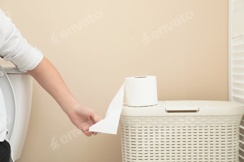 Preview: Woman taking toilet paper from roll in bathroom, closeup