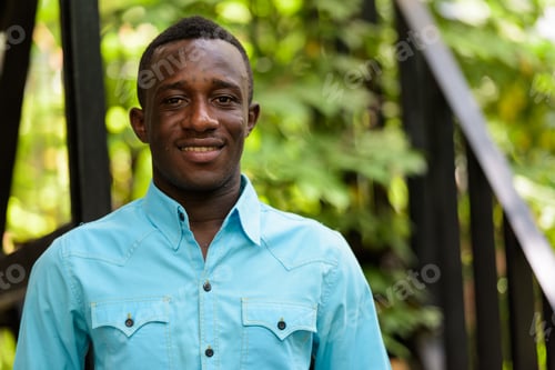 Preview: Young happy black African man smiling against modern staircase w