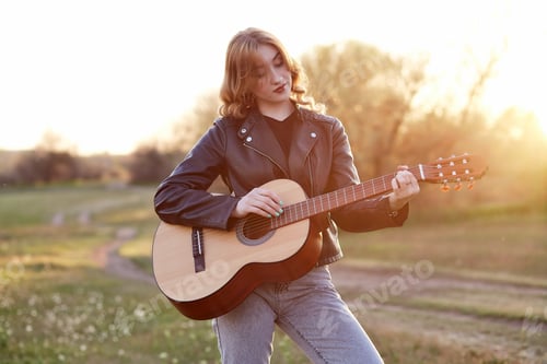 Preview: Girl with an acoustic guitar in nature in the sunset light.