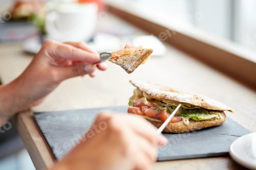 Preview: woman eating salmon panini sandwich at restaurant