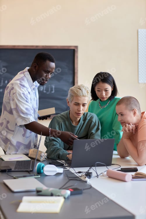 Preview: Group of four intercultural students or programmers looking at laptop screen