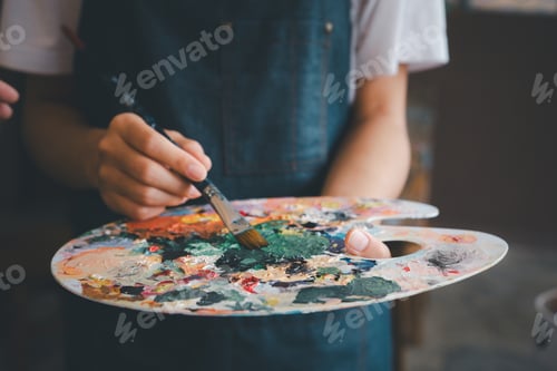 Preview: Close-up Art student's hand using a paintbrush to mix colors