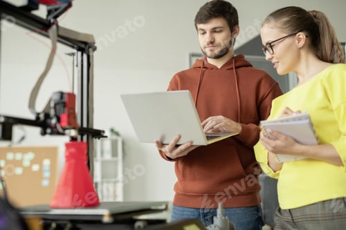 Preview: Young engineer with laptop making presentation to his pretty colleague