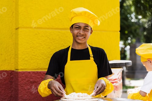 Preview: Black teen chef kneading dough outdoors, perfect restaurant promotion photo