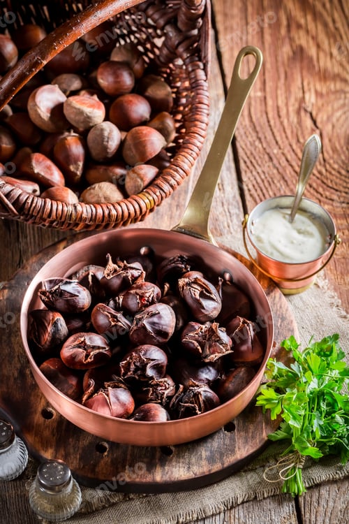Preview: Roasted chestnuts with garlic sauce on old wooden table