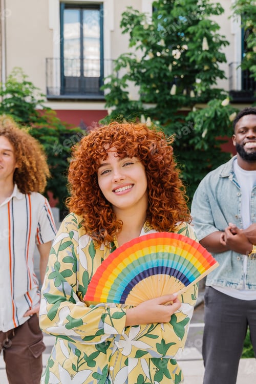 Preview: Redheaded woman embracing rainbow fan, standing with diverse friends at pride event