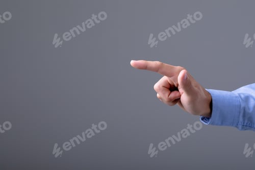 Preview: Midsection of caucasian businessman pointing with his finger, isolated on grey background