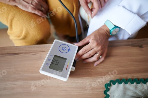 Preview: Close up of doctor monitoring mature woman blood pressure at home