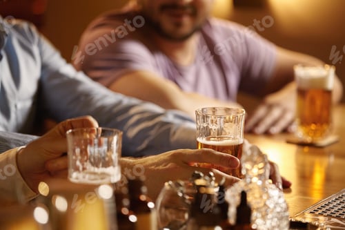 Preview: Happy young businessmen drinking beer and talking at pub after work. Cropped shot of three young men