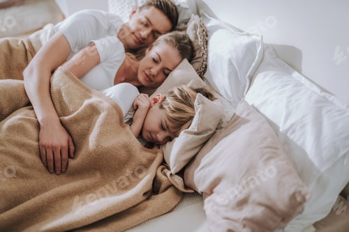 Preview: Waist Up Of Man Putting Arm On His Wife And Son While Sleeping Under One Blanket In Bed With Them