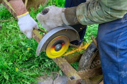 Preview: Using an angle grinder hand saw, a worker cuts metal frames