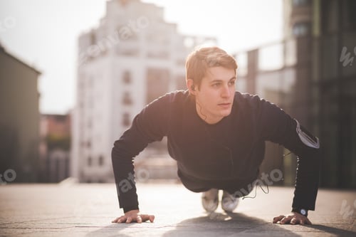 Preview: Young man doing press ups in city square