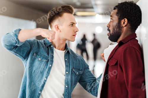 Preview: two multicultural students fighting in corridor in college