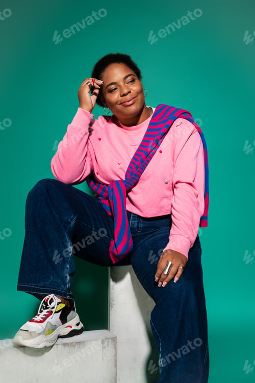 Preview: Stylish plus size woman showcasing trendy autumn fashion in a vibrant studio setting