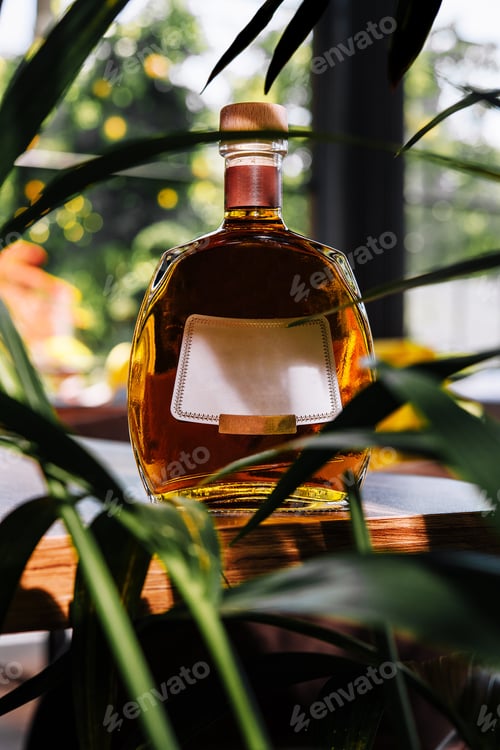 Preview: Elegant whiskey bottle with blank label amidst greenery