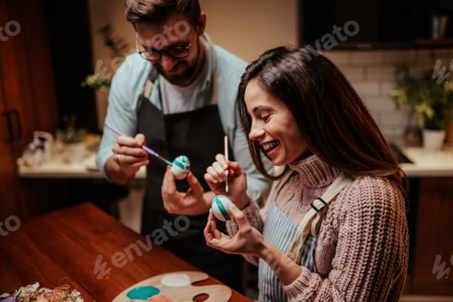 Preview: Joyful couple painting easter eggs together