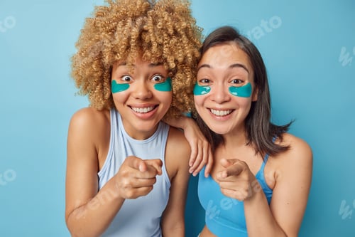 Preview: Horizontal shot of positive two young women point index fingers directly at camera choose