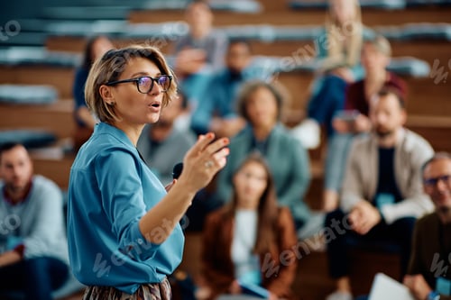 Preview: Female speaker giving a presentation during business seminar at convention center.