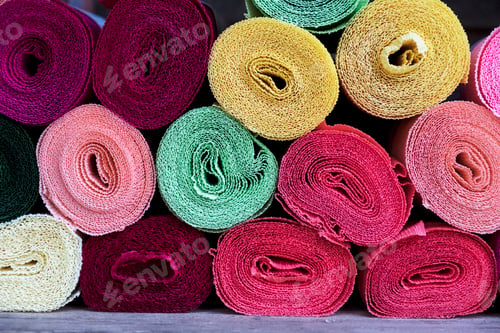 Preview: Close up of a selection of rolls of fabric in various colours.