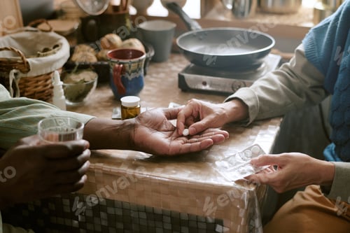 Preview: Senior Couple Taking Medication Together at Kitchen Table in Modest Home