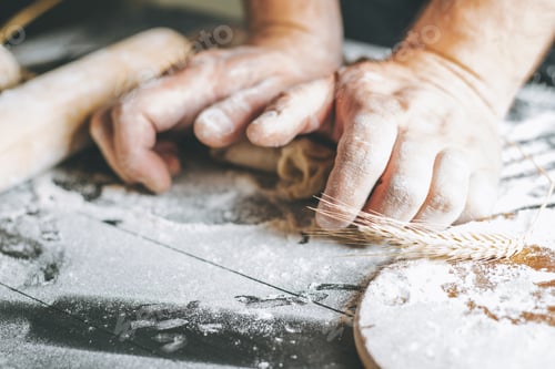 Preview: Male hands knead dough with flour next to clay pot and oil bottle and rolling pin on dark table