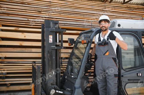 Preview: Warehouse worker gesturing thumbs up near forklift and lumber