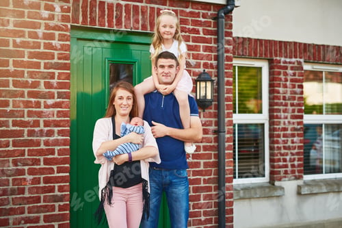 Preview: Portrait of a cheerful young family grouped together while looking at the camera outside