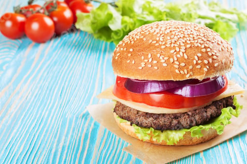 Preview: Homemade cheeseburger on blue wooden surface.