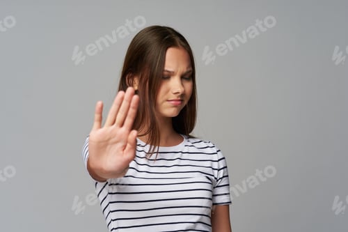 Preview: girl doing stop gesture on gray background sad face