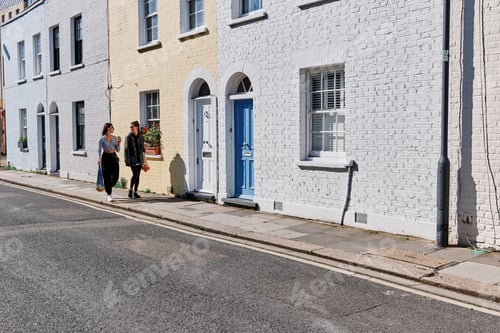 Preview: Young female friends with reusable bags chatting on street