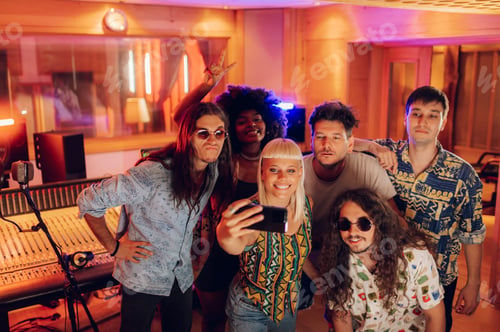 Preview: Diverse music band taking selfie with a phone while recording new album